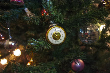 Clock on the Christmas tree with lights on the wooden backgroundの写真素材