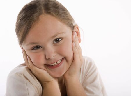 Young girl smiling with her face in her hands isolated against white background