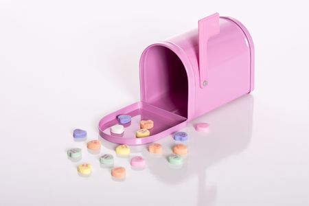 Pink mailbox surrounded by valentine candy hearts isolated against a white background.の写真素材