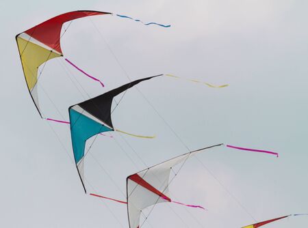 colorful kites flying  in single file in the skyの写真素材