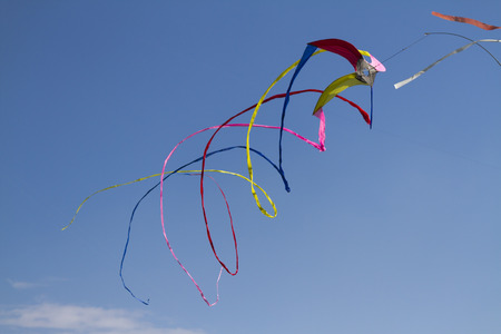 colorful kites flying  in single file in the skyの写真素材