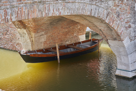 Comacchio Italy March 2017 old boat under the bridge on canalの写真素材