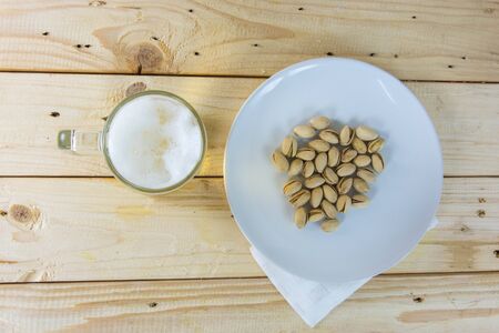 Still life with pistachios and beer in a glass on wooden table backgroundの写真素材