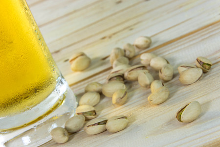 Still life with pistachios and beer in a glass on wooden table backgroundの写真素材
