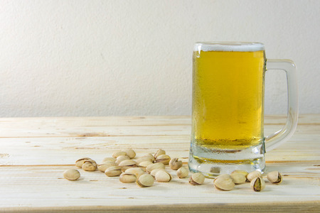 Still life with pistachios and beer in a glass on wooden table backgroundの写真素材