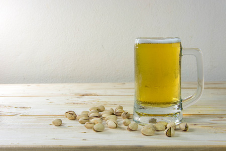 Still life with pistachios and beer in a glass on wooden table backgroundの写真素材