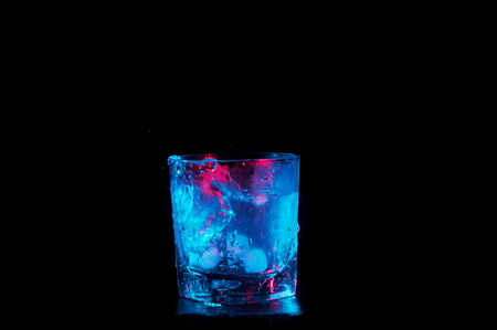 ice water glowing in blue and red lights isolated on a black backgroundの写真素材