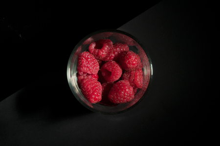 Top down view of a fancy dessert glass filled with bright and fresh red raspberries
