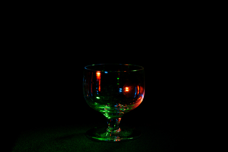Fancy empty glass in colorful lights isolated on a black backgroundの写真素材