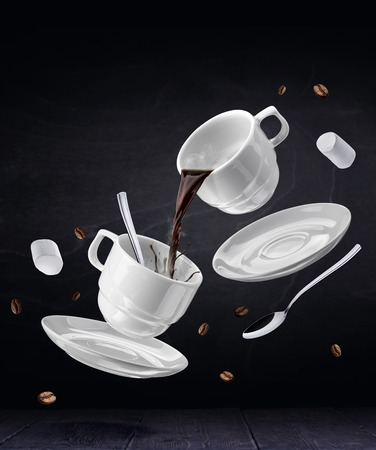 Flying cups with coffee in the bar. Coffee set on a black backgroundの写真素材