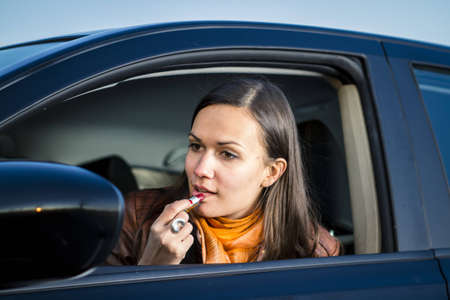 Woman applying makeup while drivingの写真素材