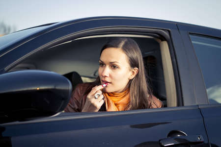 Woman applying makeup while drivingの写真素材