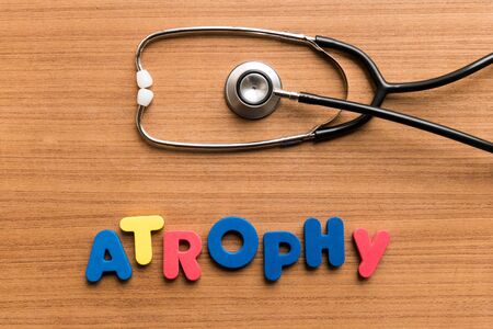 Atrophy   colorful word with Stethoscope on wooden backgroundの写真素材