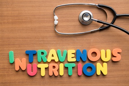 Intravenous (IV) nutrition colorful word with stethoscope on the wooden backgroundの写真素材