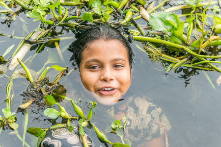 Munshigonj, Bangladesh - July 29, 2016: Children taking bath in a pond to beat the heat of scorching...
