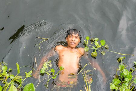 Munshigonj, Bangladesh - July 29, 2016: Children taking bath in a pond to beat the heat of scorching sun, on July 29, 2016 in in the village of Munshogonj, bangladesh.のeditorial素材