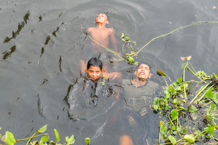 Munshigonj, Bangladesh - July 29, 2016: Children taking bath in a pond to beat the heat of scorching sun, on July 29, 2016 in in the village of Munshogonj, bangladesh.のeditorial素材