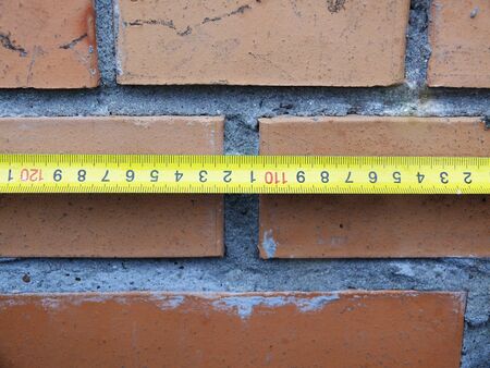 measuring the size of a brick wall on a building roof.