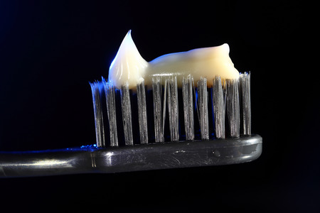 toothbrush on a black background with cream colored paste.