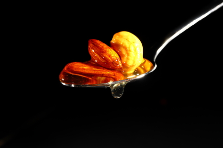 Honey and nuts in metal spoon isolated on black background..の写真素材