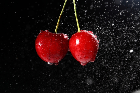 Cherries with water drops on black background.