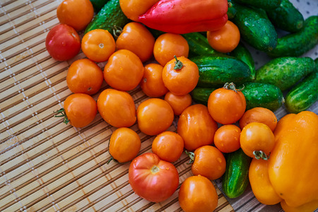 Tomatoes, cucumbers, red and yellow peppers on the table.