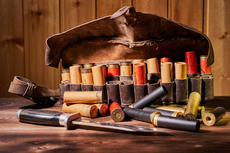 Old hunting cartridges and bandoleer on a wooden table.