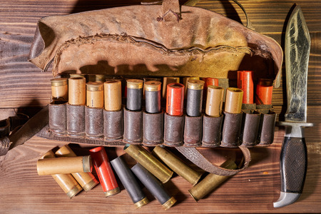 Old hunting cartridges and bandoleer on a wooden table.