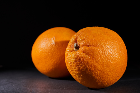 two ripe and juicy oranges on a black background.の写真素材