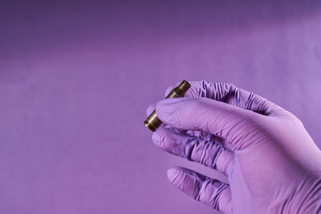The hand of a man in a glove holding a bullet shell.の写真素材