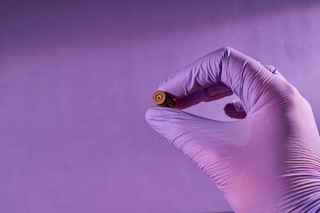 The hand of a man in a glove holding a bullet shell.