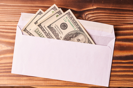American dollars in a white envelope. Wooden background.の写真素材