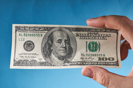 Man's hand holding dollars, top view. Blue background.の写真素材