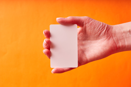 A woman's hand holds a white plastic card. Isolated card in hand.の写真素材