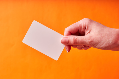 A woman's hand holds a white plastic card. Isolated card in hand.の写真素材