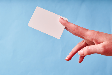 A woman's hand holds a white plastic card. Isolated card in hand.の写真素材