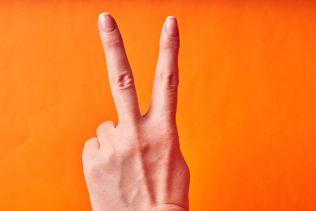 Female hand on orange background showing a gesture of good luck.の写真素材