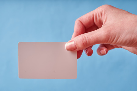 A woman's hand holds a white plastic card. Isolated card in hand.の写真素材