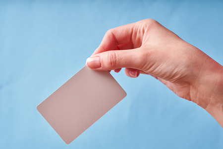A woman's hand holds a white plastic card. Isolated card in hand.の写真素材