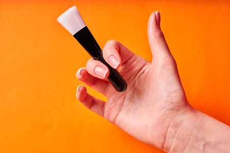Beautiful well-groomed female hand with a brush for cosmetic procedures.の写真素材