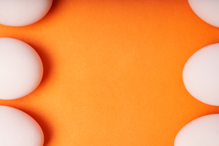 Chicken eggs laid out on an orange background.