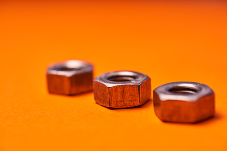 hex nuts on orange background. Bolted connection elements.