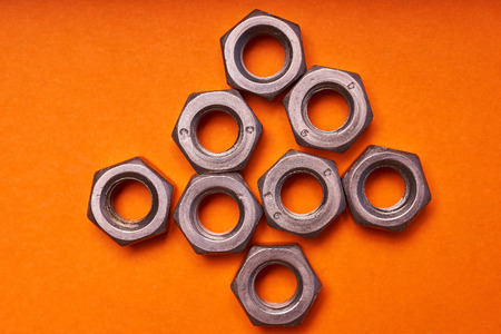 hex nuts on orange background. Bolted connection elements.