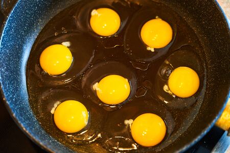 Seven raw eggs in a pan, ready to fry.
