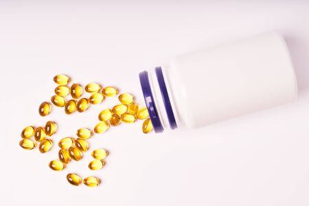 White bottle with scattered vitamins on white background.の写真素材