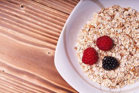 Cereal porridge with fresh berries on a wooden table.の写真素材