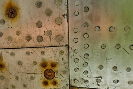 Aluminum surface of the aircraft fuselage. Smooth rows of rivets, there are scratches, dirt.