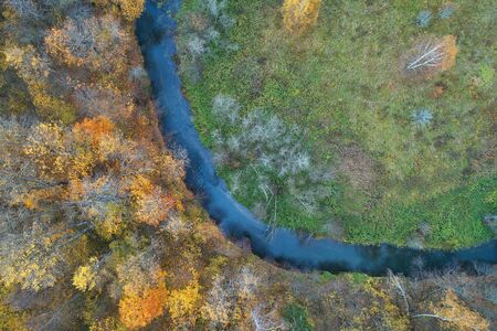 Aerial view with a drone. Winding river with autumn forest, top view.の写真素材
