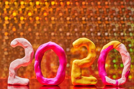 2020 New year design concept. Colored figures of plasticine on a Golden background.の写真素材