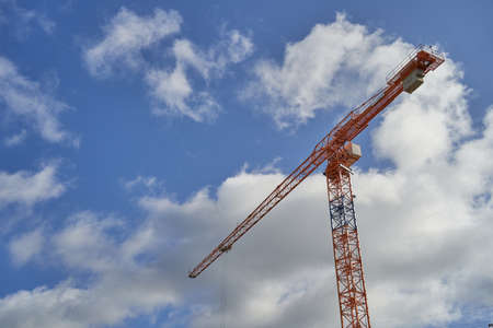 Construction tower crane against a blue sky with clouds.の写真素材